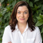 Woman with dark brown and white button-down shirt looking at the camera